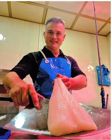 Alfredito sosteniendo un lomo de pescado blanco